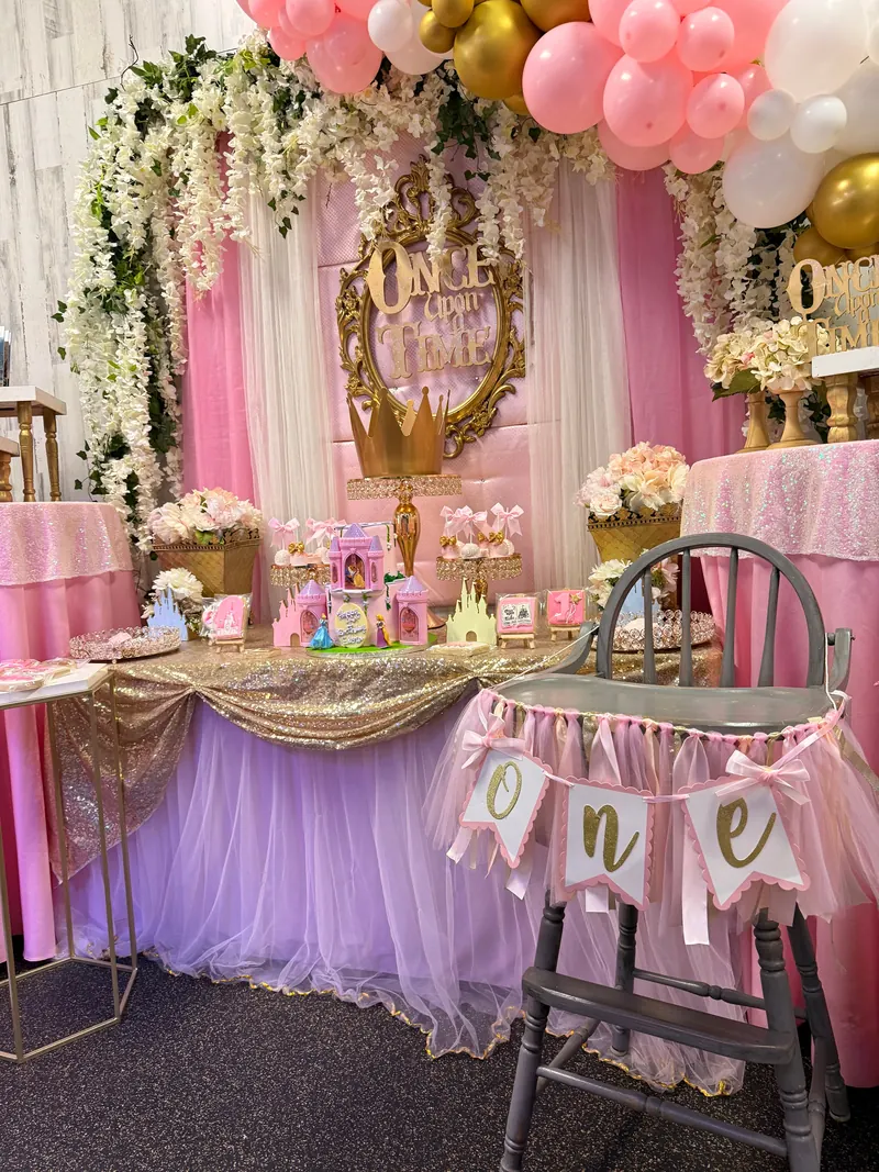 Elegant gold and pink birthday setup with floral backdrop at Millie Moo's