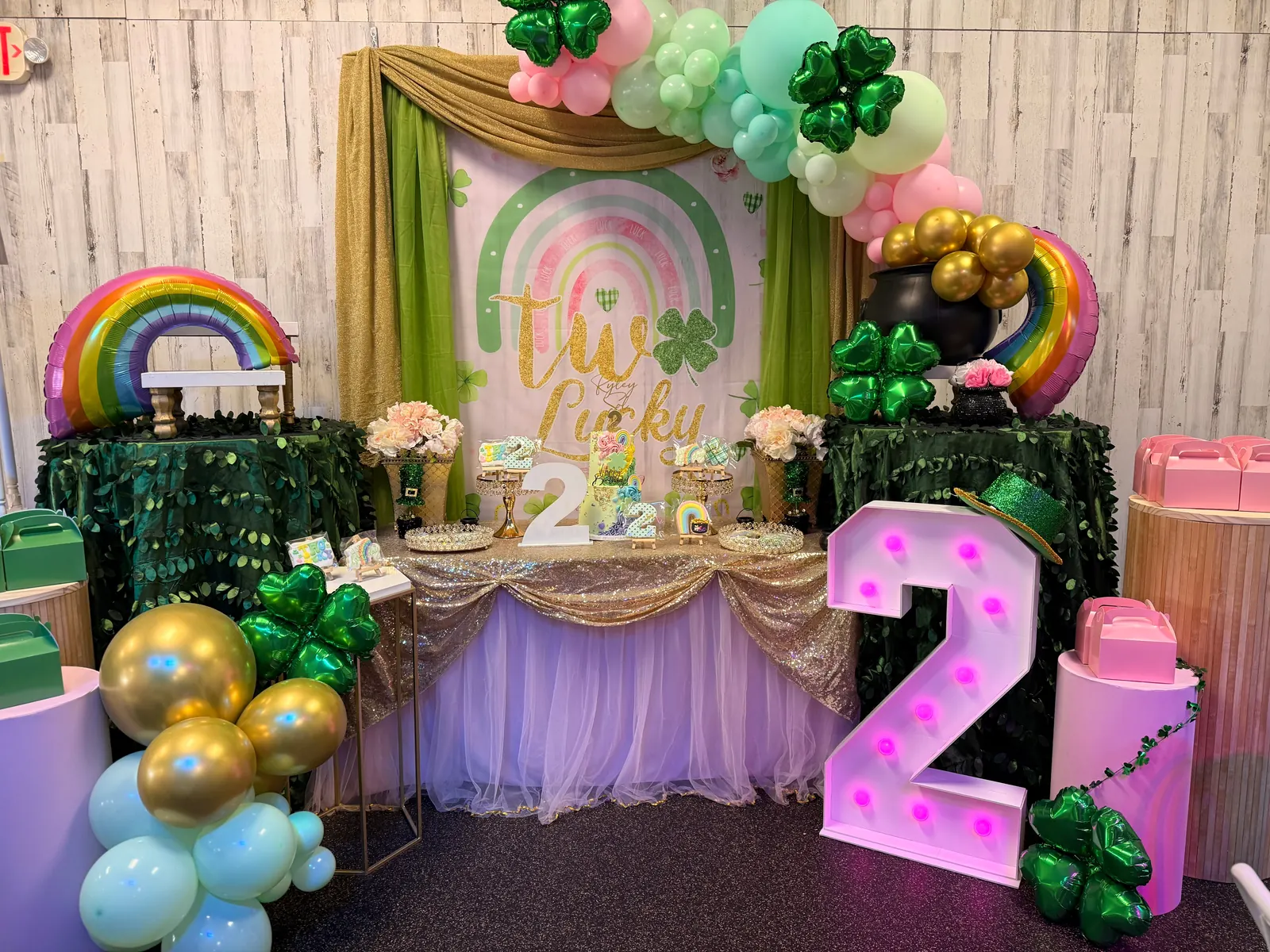 A rainbow-themed birthday party setup at Millie Moo's with a balloon arch and dessert table