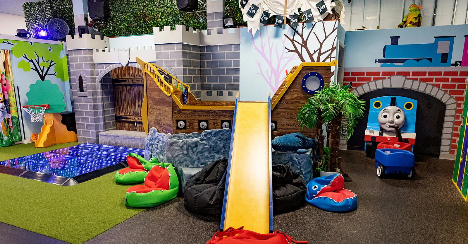 The castle play structure, light-up dance floor, and train tunnel at Millie Moo's