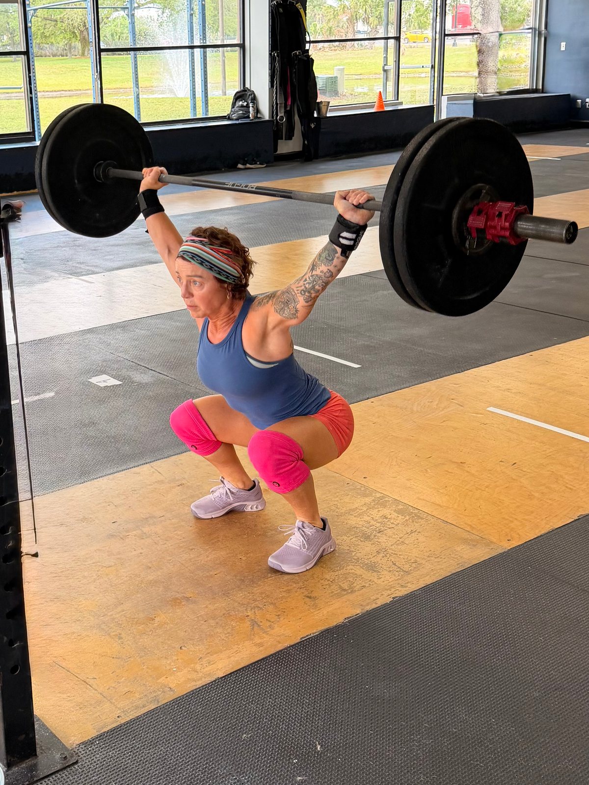 An athlete holding a loaded barbell overhead at the bottom of an overhead squat
